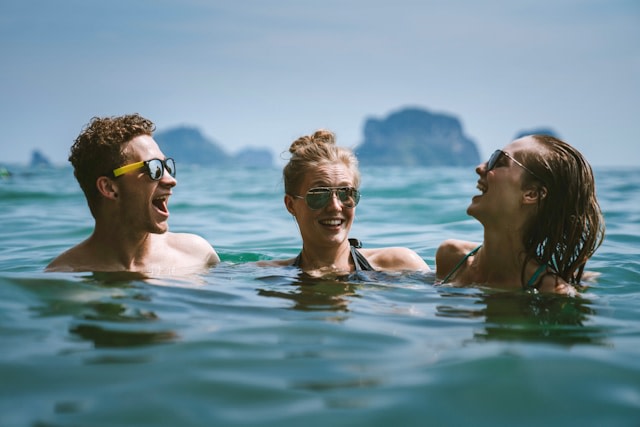 Ein junger Mann und zwei junge Frauen schwimmen gemeinsam im Meer, von Trend via @unsplash