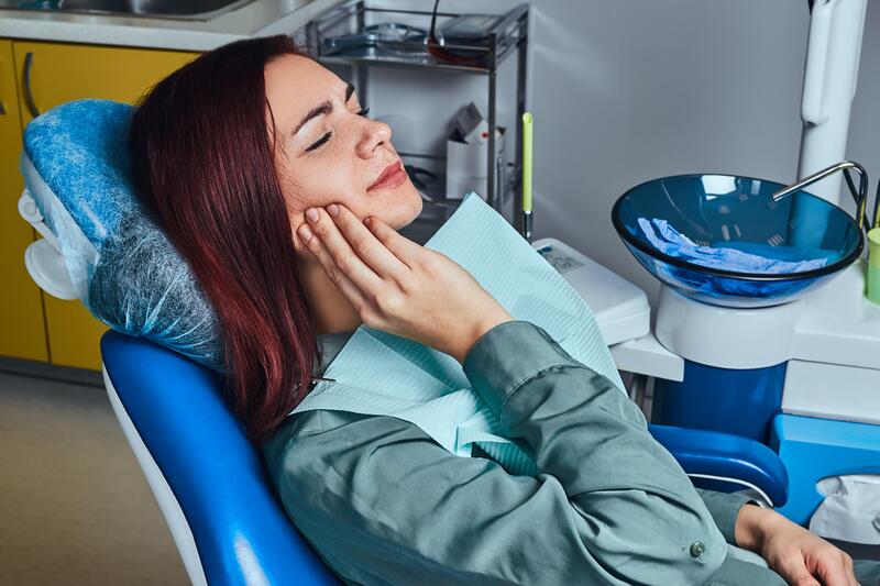 Paziente donna in poltrona ortodontica con mal di denti