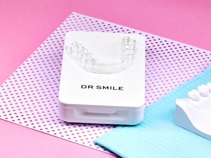DR SMILE Zahnschiene liegt auf der Aufbewahrungsbox vor pinkem Hintergrund