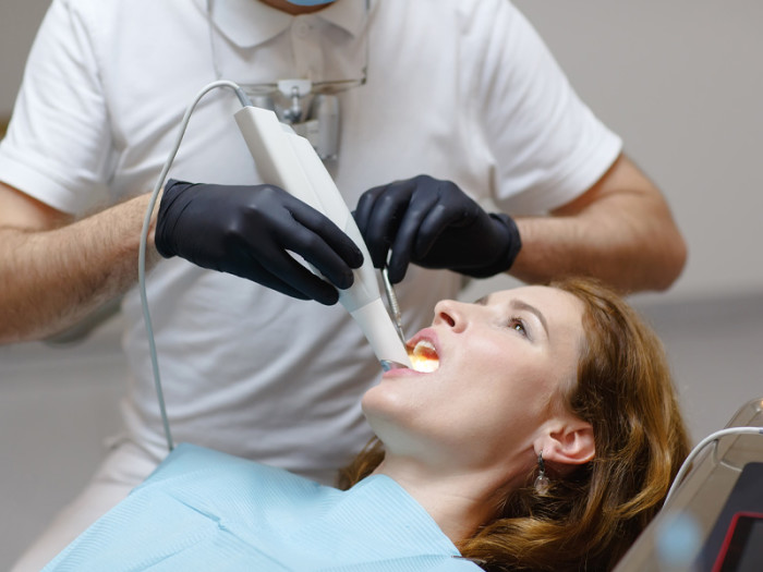 Dentista realizando escáner intraoral a una mujer en clinica
