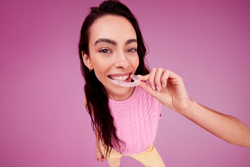 Femme mettant un aligneur dentaire DR SMILE en place sur sa dentition