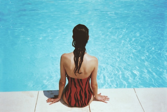 Frau sitzt im Badeanzug am Beckenrand eines Pools von Margot Pandone via @unsplash