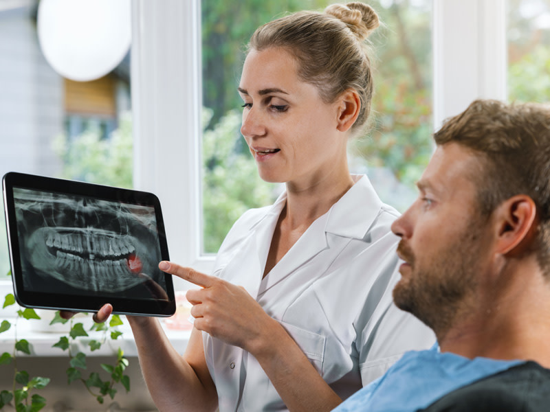 Dentista y paciente mirando una radiografia de la boca