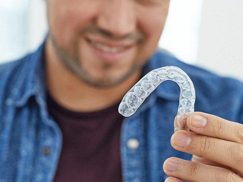 Gros plan d'un aligneur dentaire DR SMILE tenu par un patient