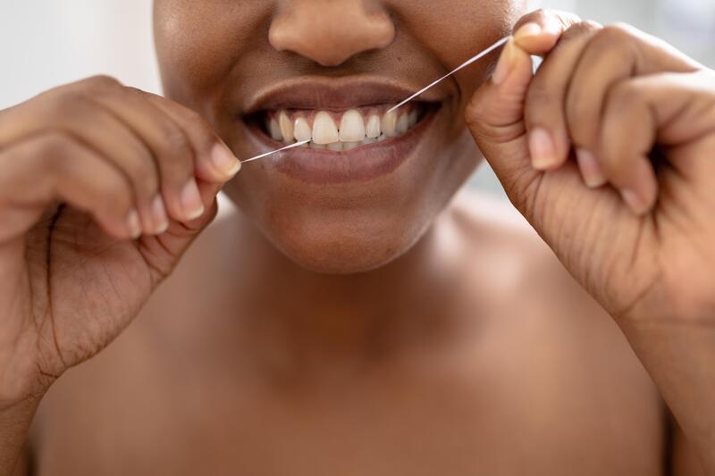 Gros plan sur les dents d'une femme utilisant du fil dentaire
