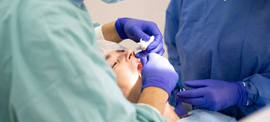 Patient liegt während einer Zahn OP auf dem Behandlungsstuhl und wird vom Zahnarzt behandelt, Foto von bruno141990 auf pixabay
