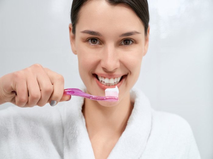 Mujer cepillándose los dientes blancos