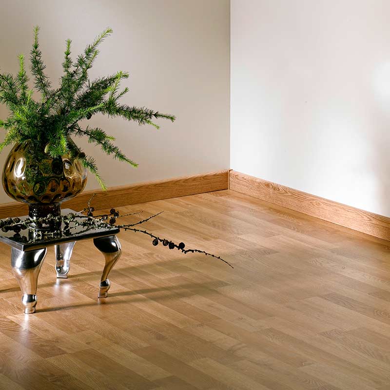 Vaalea nurkka puulattialla ja seinillä, metallipöydällä ruskea maljakko, vihreä oksa, mustat marjat