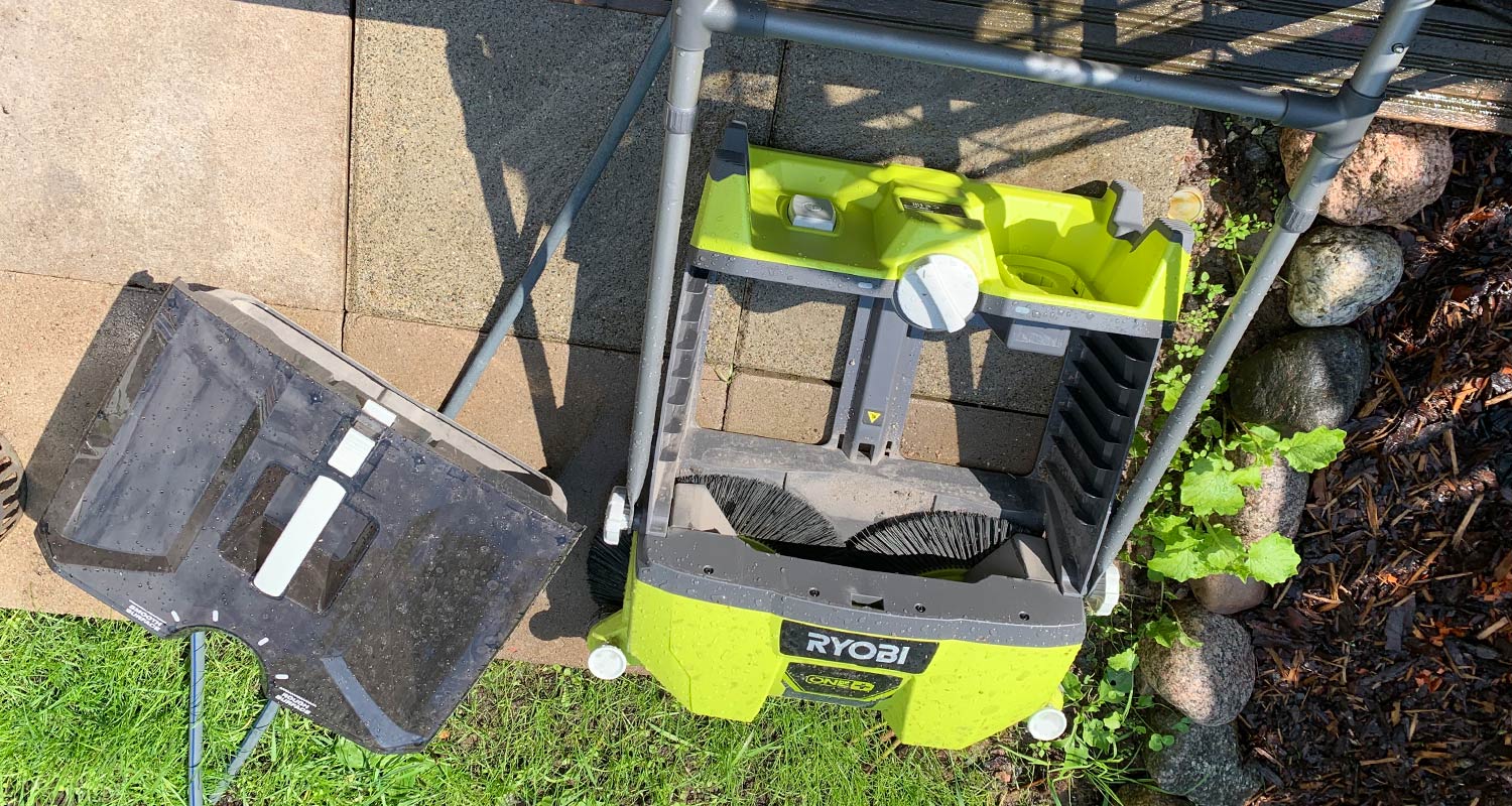 Ryobin lakaisukone avattuna pihamaalla, säiliön tyhjennys