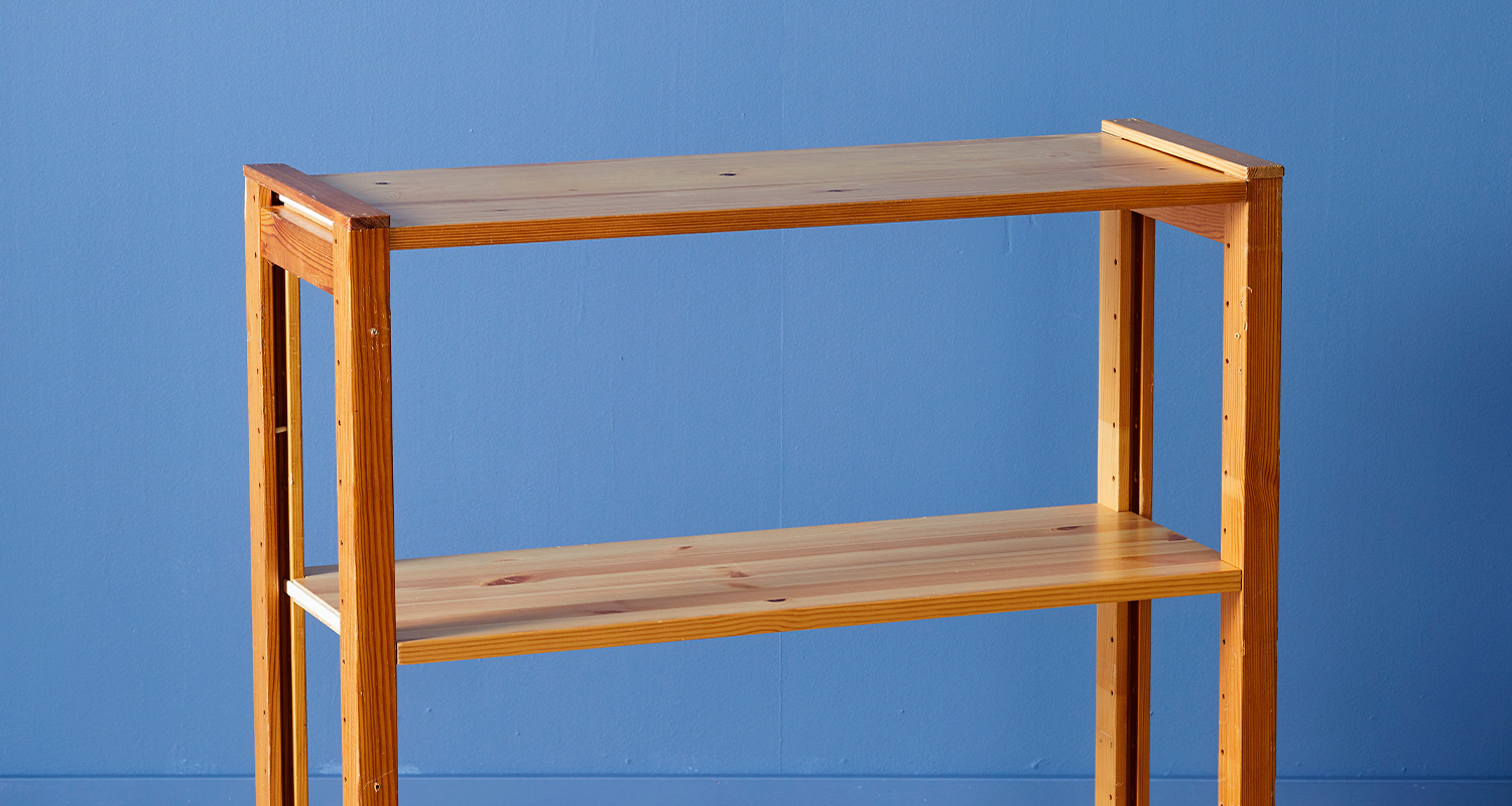 Vaalea puinen kaksitasohylly sinistä seinää vasten