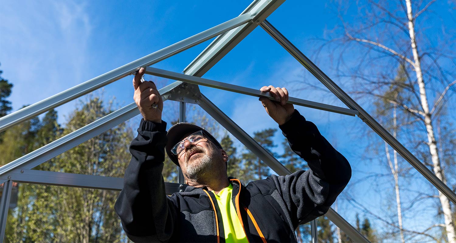 Mies rakentaa kasvihuonetta K-Raudan ohjeilla.