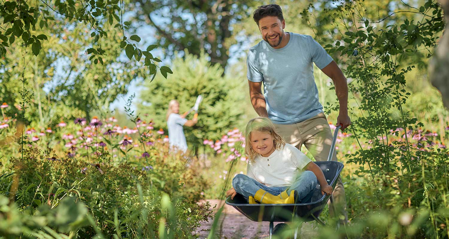 Huolettomat istutukset ja perhe vehreällä pihamaalla