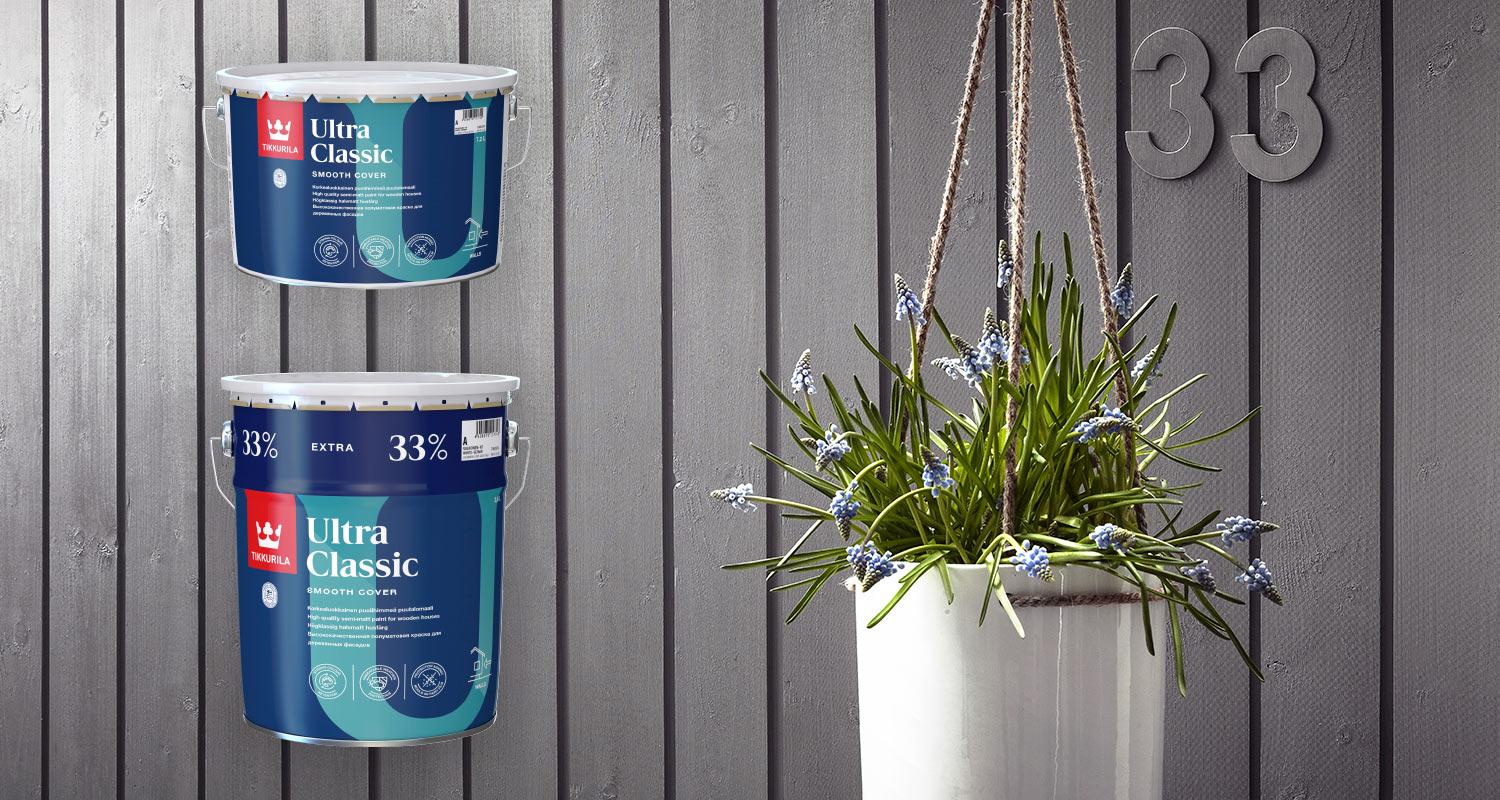 Harmaaksi maalattu talon puinen ulkoseinä ja Tikkurila Ultra Classic -talomaalipurkit
