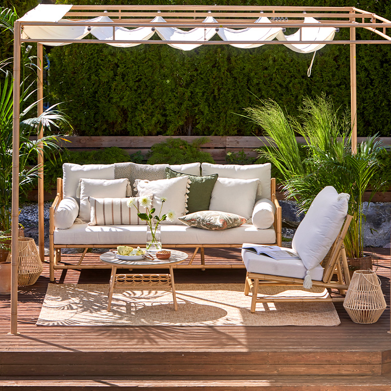 Terassi sisustettu K-Raudan Cello-terassikaluisteilla. Kuvassa sohva, pöytä, nojatuoli sekä pehmusteita. Kalusteet ovat puisen pergolan sisällä.