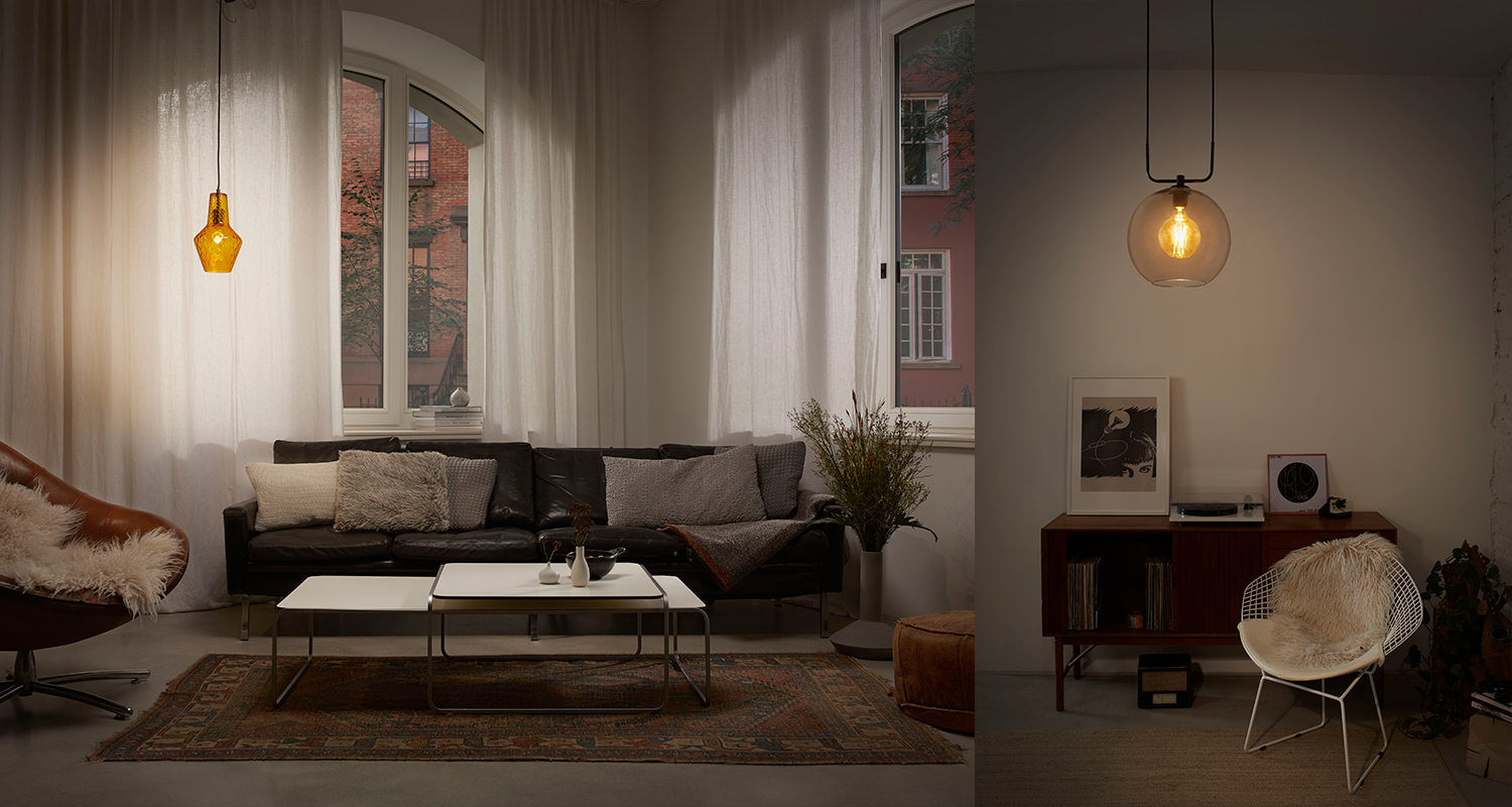 Olohuone: musta nahkasohva, valkoiset verhot kaarevien ikkunoiden edessä, kaksi kattovalaisinta.