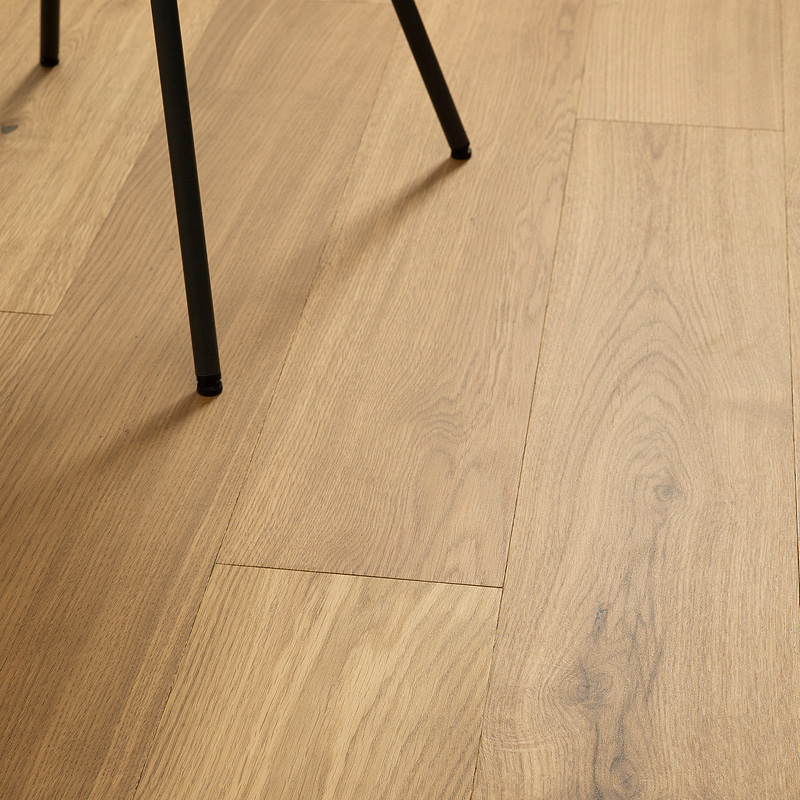 Kuvassa puunväristä kovetettua puulattiaa ja mustan tuolin jalat.