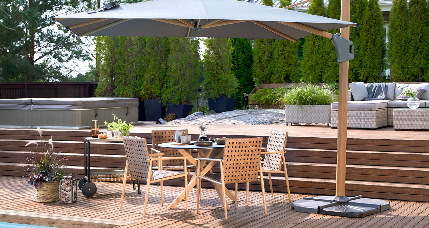 Terassi sisustettu K-Raudan Cello-terassikaluisteilla. Kuvassa ruokapöytä, tuoliryhmä sekä suuri aurinkovarjo.