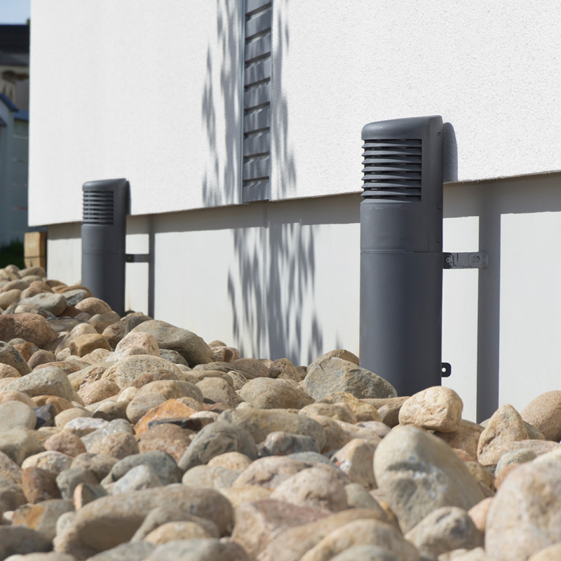 Valkoisen seinän vieressä rusehtavia pyöreitä kiviä ja kaksi harmaata venttiiliä.