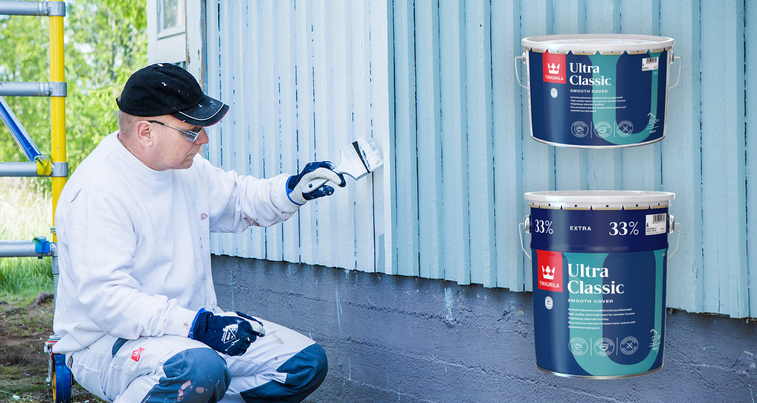 Maalari maalaa puutalon ulkoseinää siniseksi sävytetyllä Tikkurilan Ultra Classic -talomaalilla, joka on myynnissä K-Raudassa