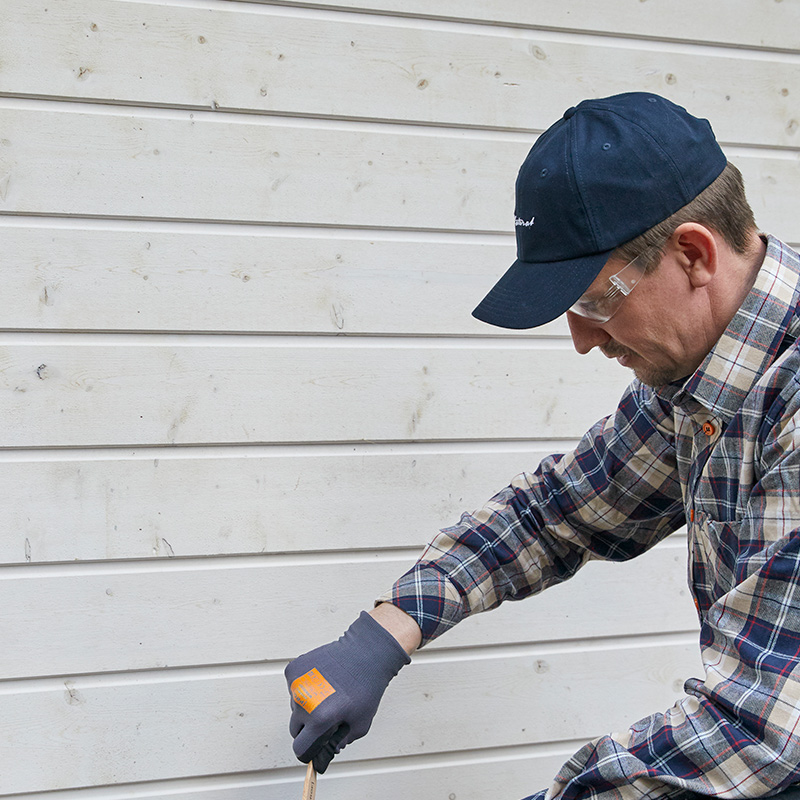 Mies maalaa talon ulkoseinää