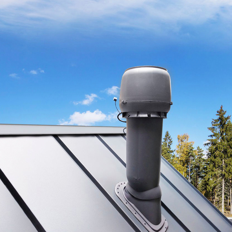 Harmaa kattotuulettimen putkikorkki hopeanharmaalla peltikatolla, sinitaivas ja metsänreuna