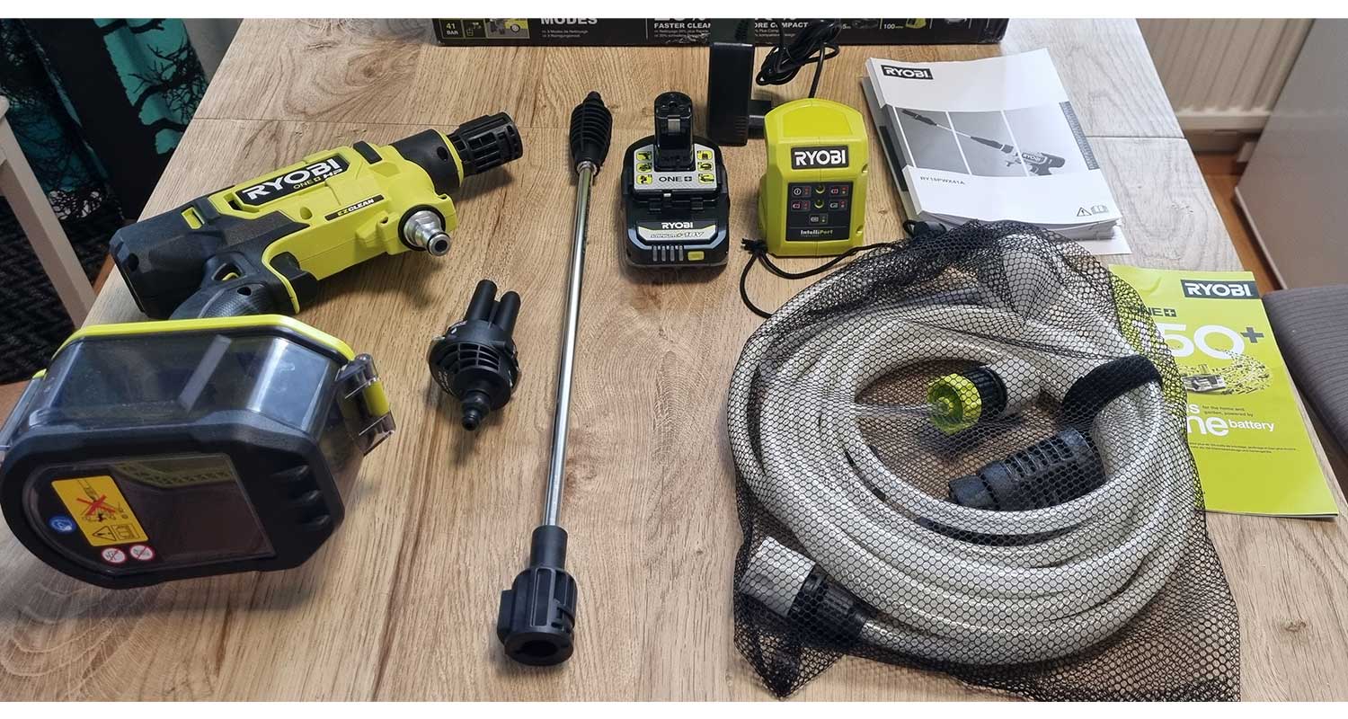 tuotetestissä kuluttajalla akkupainepesuri Ryobi RY18PWX41A-125 18V, pakkauksen osat pöydälle levitettynä