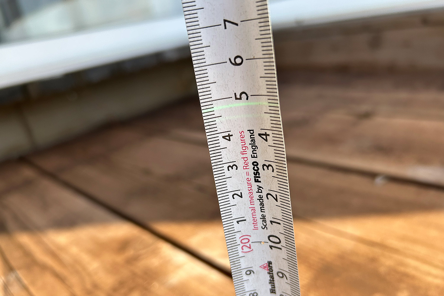 Auringonvalossa linjalaserin viiva erottuu vihreänä mittanauhassa.