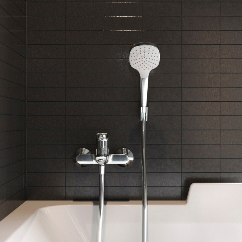 Krominen suihkuhana ja käsisuihku mustaa laattaa vasten valkoisen kylpyammeen reunalla