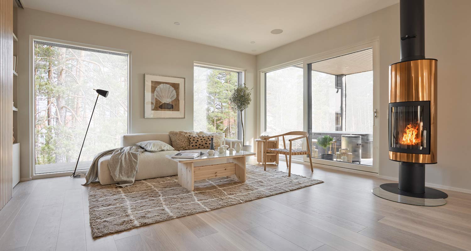 Vaalea skandinaavinen olohuone suurella ikkunalla, puupöytä, beige-sohva ja kuparinvärinen takka.