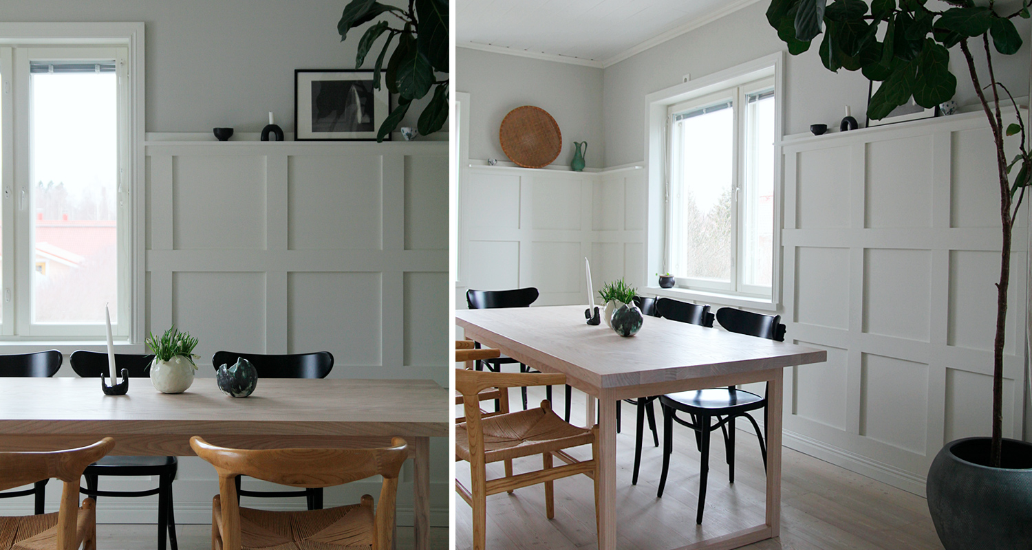 Vaalea moderni ruokailuhuone, vaalea puupöytä, mustat ja puunväriset tuolit, ikkuna, paneeliseinä, viherkasvi