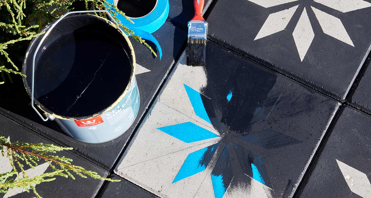 Betonilaattoja sinisellä teipillä ja mustalla maalilla tähtikuviolla, vieressä sivellin ja maalipurkki