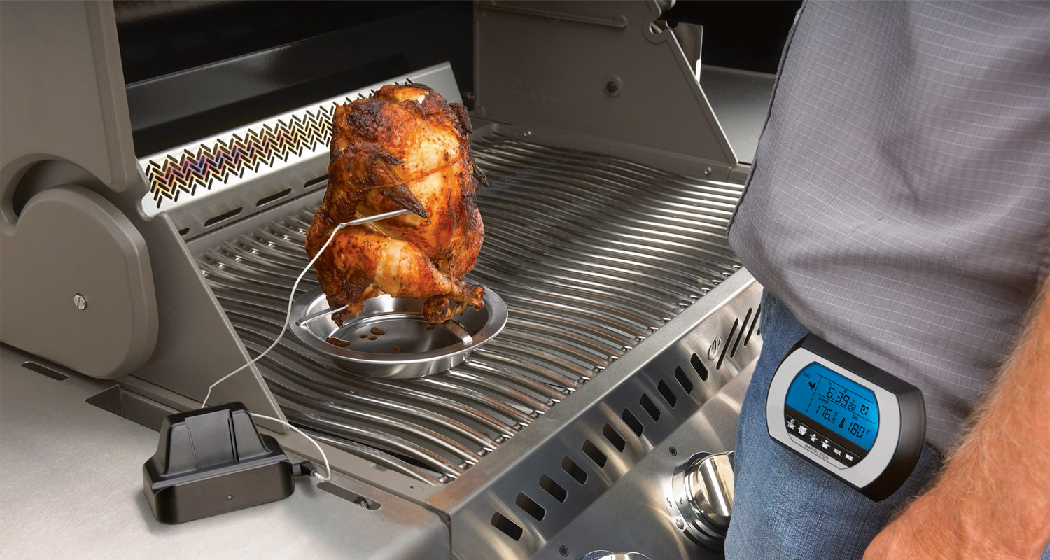 Hopeanvärisessä grillissä ruskistuva kana lämpömittaripronkalla ja sinisellä diginäytöllä