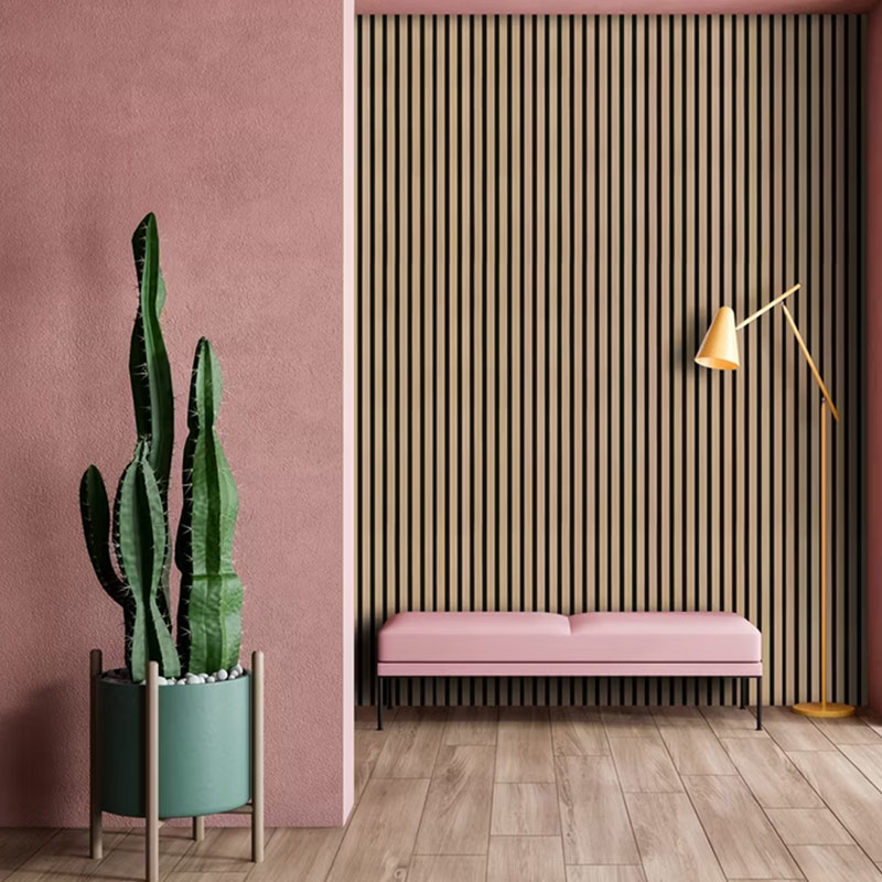 Vaaleanpunainen penkki puulistasäleikön edessä, kaktus vihreässä ruukussa ja kultainen lattiavalaisin.