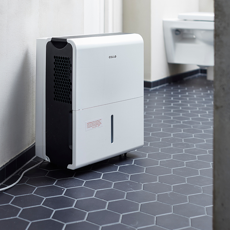 Valkoinen Cello-ilmankuivaaja mustalla ritilällä tummanharmaalla kuusikulmalaattalattialla