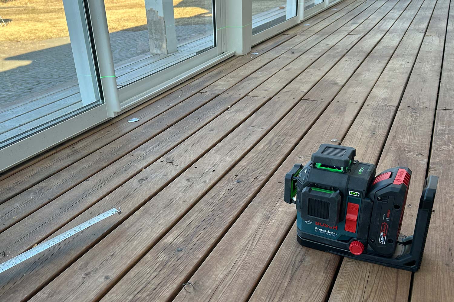 Bosch-linjalaser GLL 18V-120-33 CG -mallin viiva näkyy selkeästi karmeissa, terassinlasien säätö menossa. Tuote löytyy K-Raudasta.