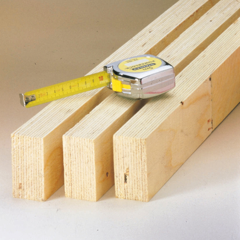 Kolme vaaleaa puupalkkia, päällä kromipintainen mittanauha keltainen nauha vedetty noin 10 cm.