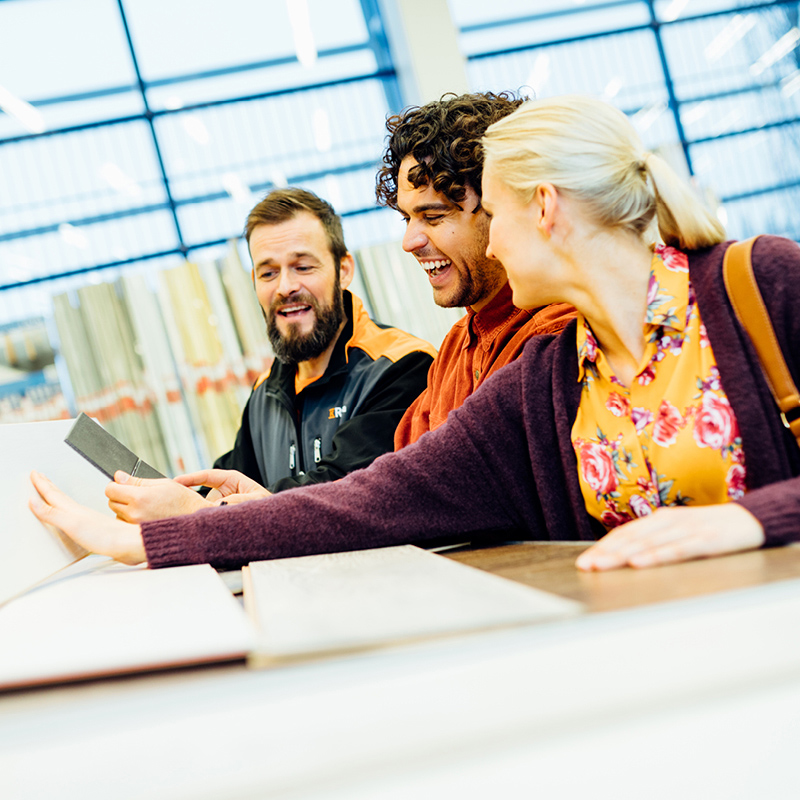 Kuvassa asiakkaat katsomassa eri pintamateriaalivaihtoehtoja K-Raudassa myyjän kanssa.