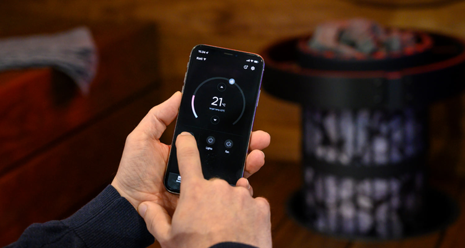 Käsi älypuhelimella, ruudulla lämpötilasäädin 21 °C ja valot/tuuletin-painikkeet