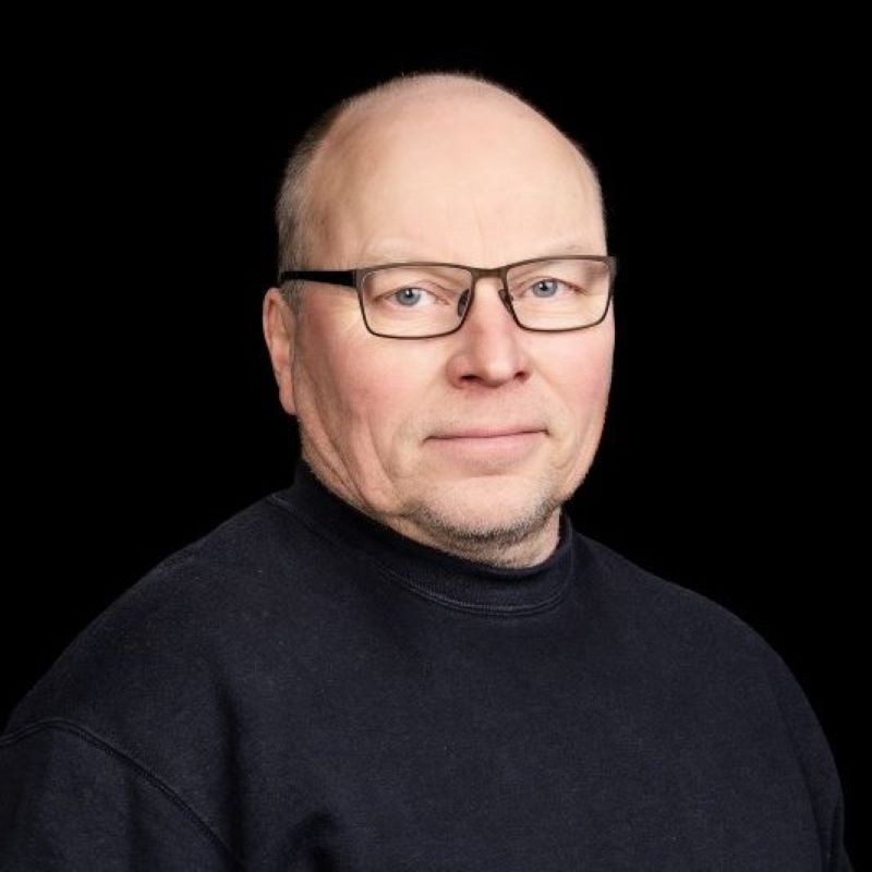 Kalju mies silmälaseissa mustassa collegepaidassa mustaa taustaa vasten