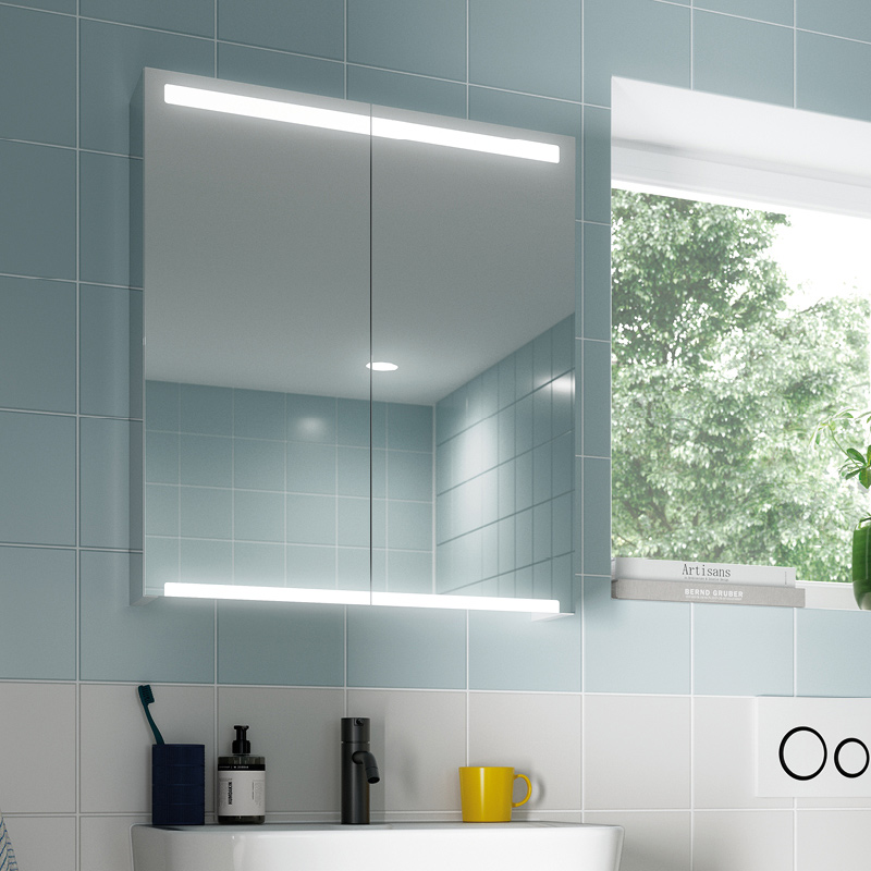 Kylpyhuoneen sinivalkoiset laatat, valaistu peilikaappi, musta hana ja keltainen muki.