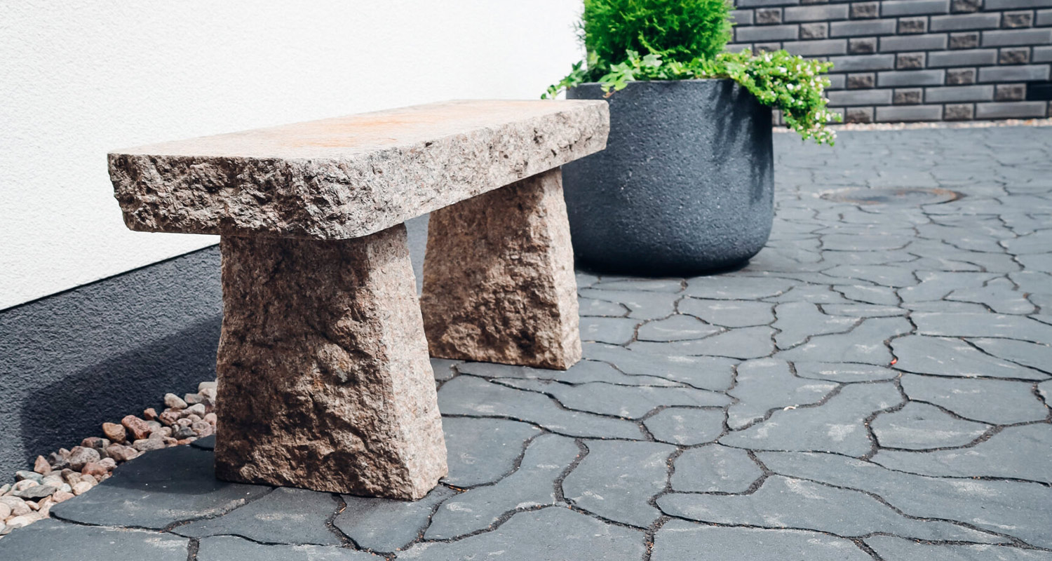 Kivipatio sekä kivestä tehty penkki ja kukkaruukku.