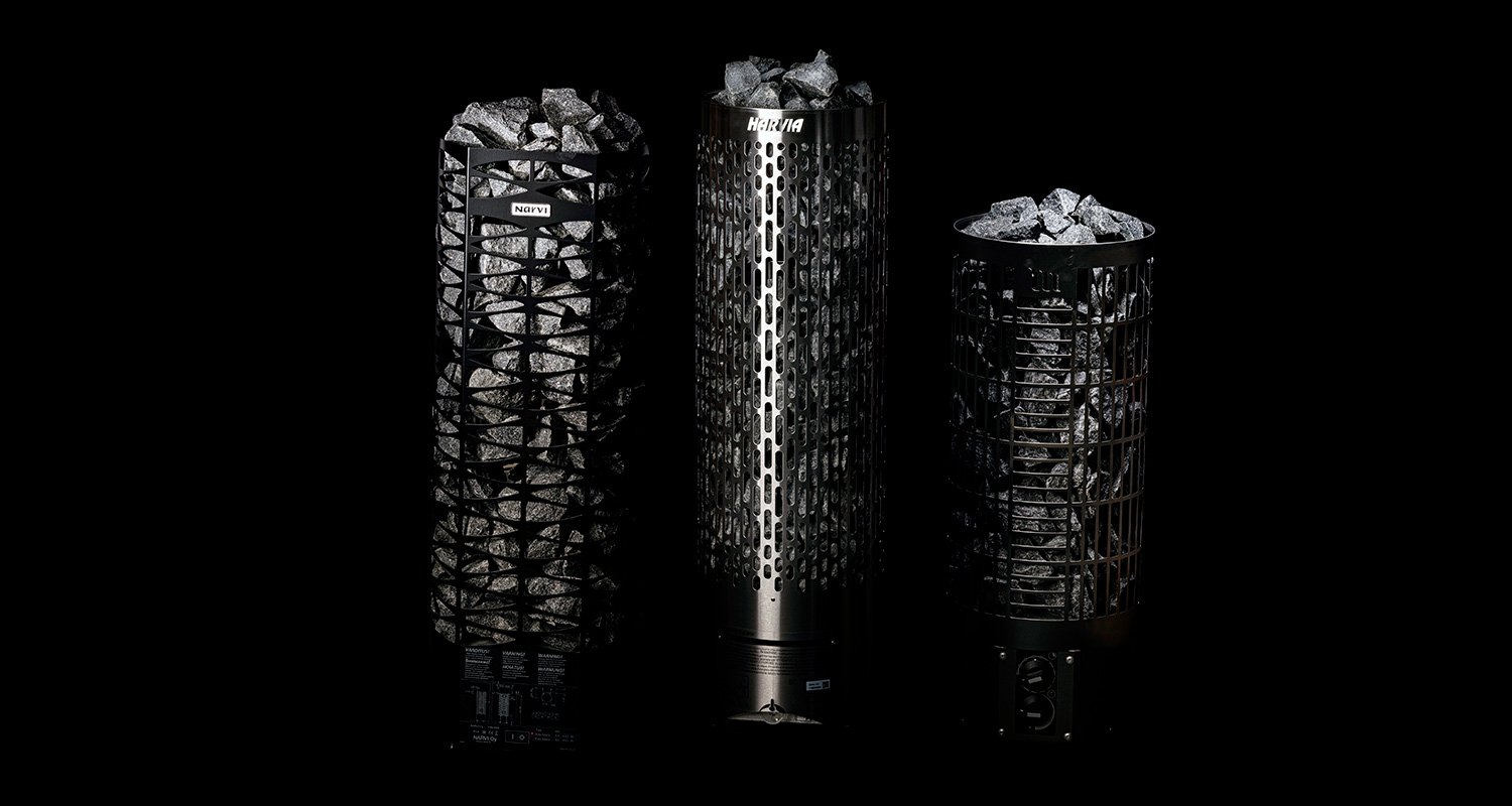 Kolme mustaa metallista saunakiuasta harmaine kiuaskivineen tummalla taustalla.