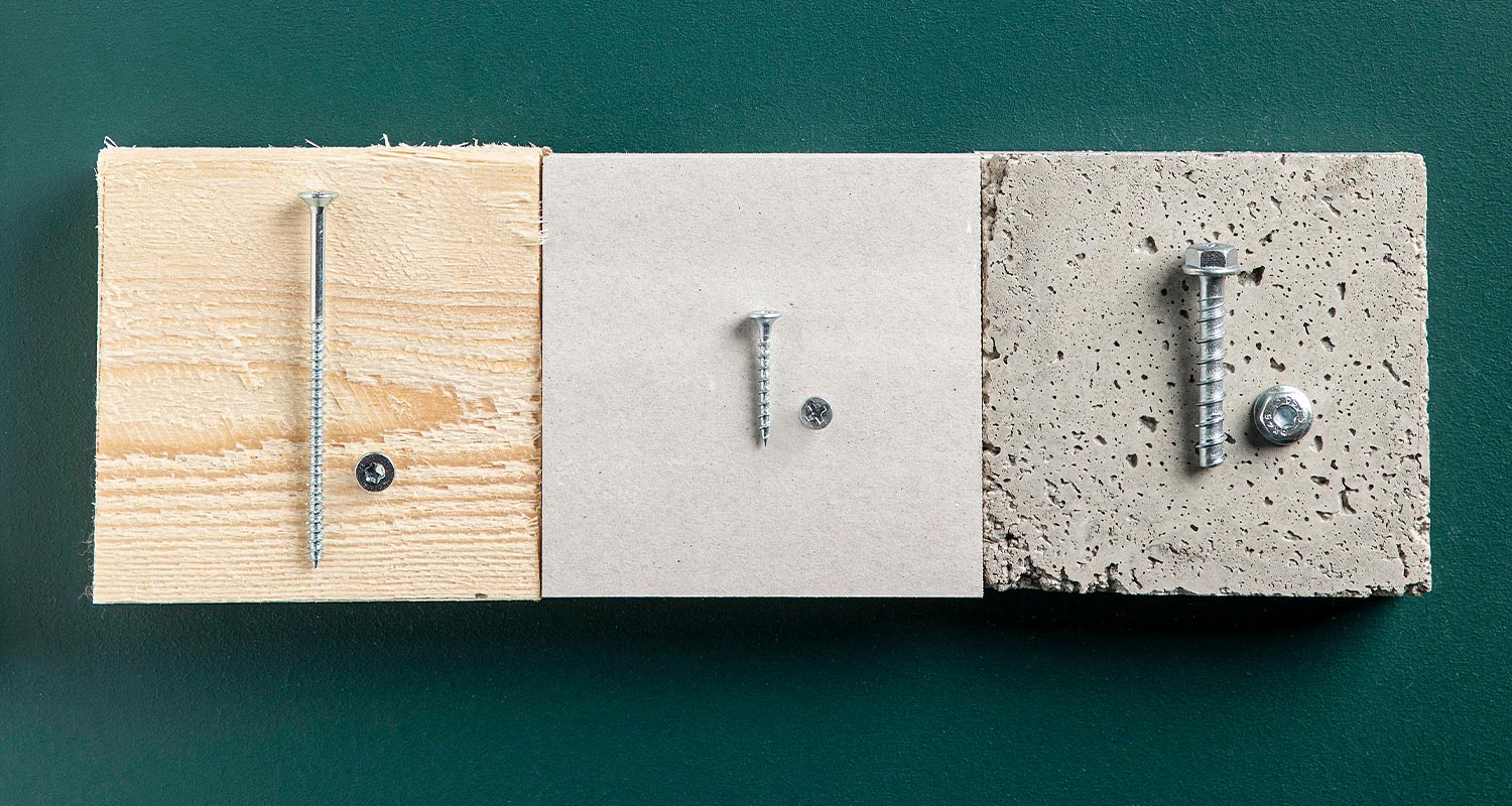 Kolme materiaalinäytettä (puu, kipsilevy, betoni) vihreällä taustalla, joissa eri ruuvit.