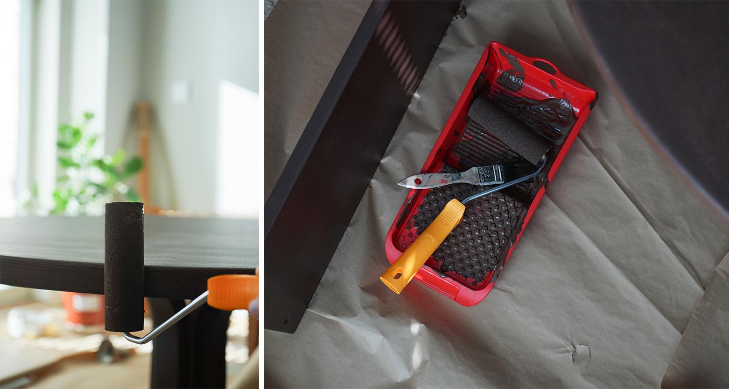 Mustaksi maalattu pöydänreuna, punainen maaliastia, oranssinkahvainen tela ja harja.