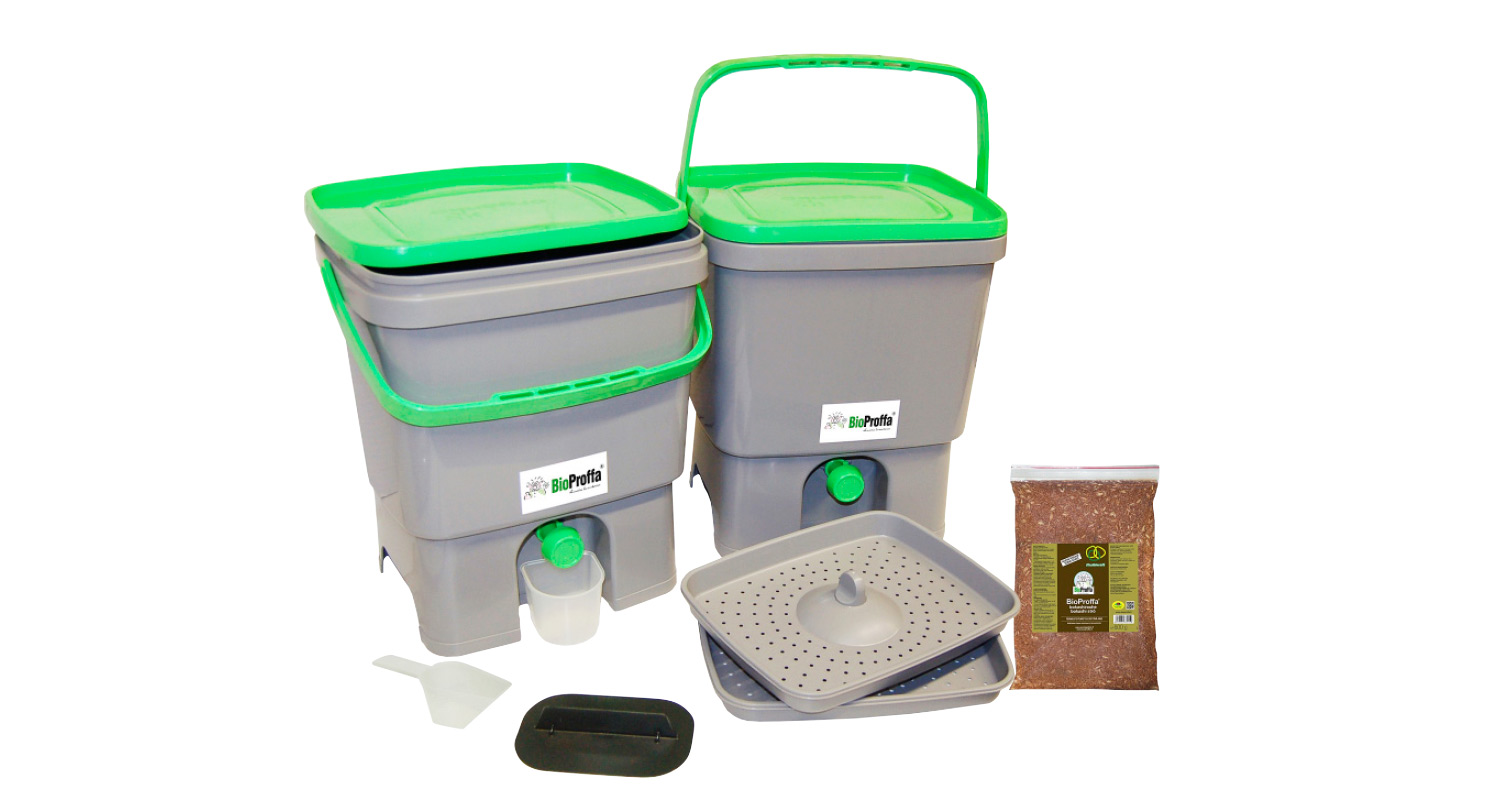 Kaksi harmaata ja vihrein kansin BioProffa-keittiökompostoria, ritiläalustat, kauha ja kompostimulta