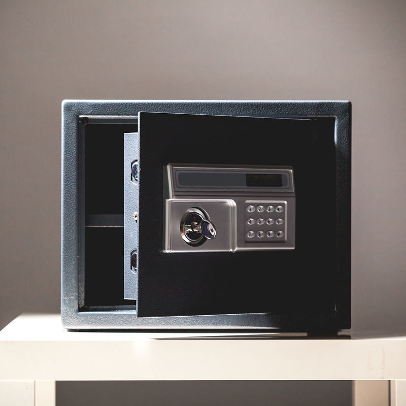 Avattu musta kassakaappi hopeisella näppäimistöllä ja avaimella valkoisella pöydällä