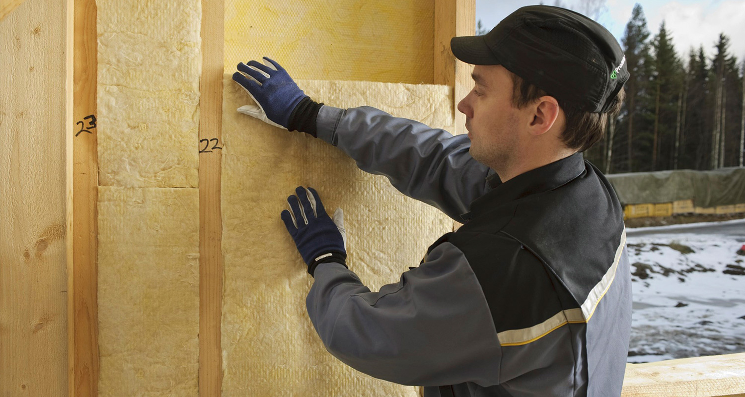Mies asentamassa lisäeristettä omakotitalon seiniin.