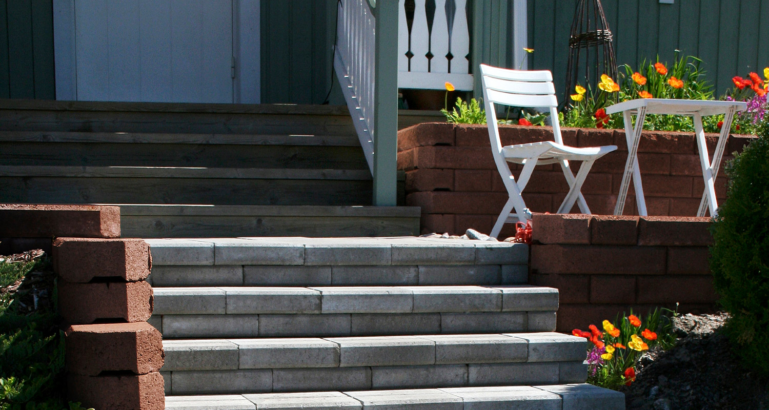 Harmaat kiviportaat puisen omakotitalon edessä.