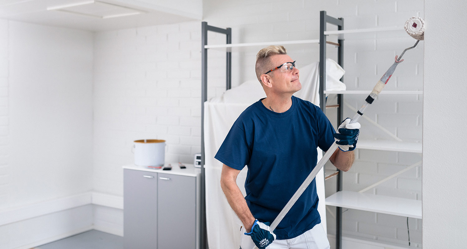 Maalari maalaa seinää vaaleaksi telalla