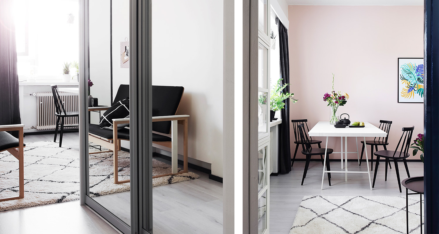 Vaalea olohuone ja vaaleanpunainen ruokailutila mustilla tuoleilla, valkoinen pöytä, kasveja.